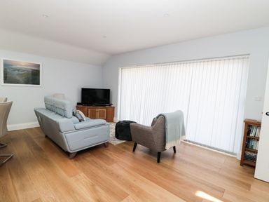 A living room with a couch a chair a television and a wooden cabinet at 3 The Paddock in Benthall near Beadnell