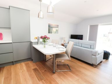 A kitchen and living room with a dining table set with plates and chairs at 3 The Paddock in Benthall near Beadnell