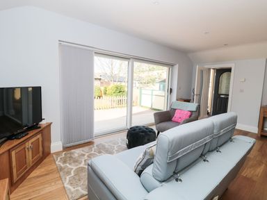 A living room with a blue sofa a chair and a TV on a wooden stand at 3 The Paddock in Benthall near Beadnell