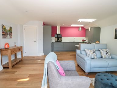 An open living room and kitchen with a gray armchair and blue sofa at 3 The Paddock in Benthall near Beadnell