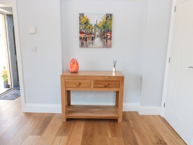 A wooden console table with two drawers with a salt lamp and reed diffuser on top in a hallway at 3 The Paddock Benthall near Beadnell