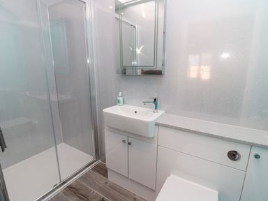 A bathroom with a shower enclosure a sink with a faucet a mirror and a countertop with cabinets at 3 The Paddock in Benthall near Beadnell