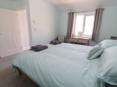 A bedroom with a bed with folded towels a desk with a sewing machine and a window with curtains at 3 The Paddock in Benthall near Beadnell
