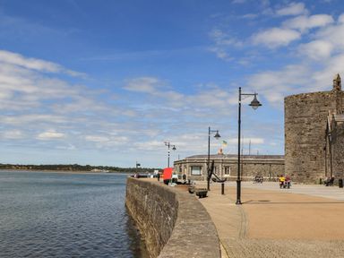 A waterfront walkway with a stone wall and historic stone buildings at Llety Pen Deitsh 1 in Caernarfon