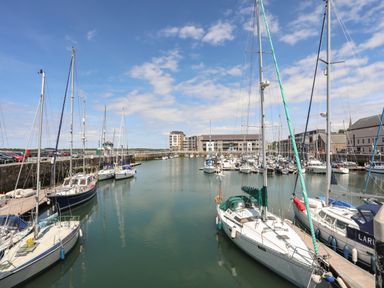 A marina with sailboats docked along piers and buildings in the background at Llety Pen Deitsh 2 in Caernarfon