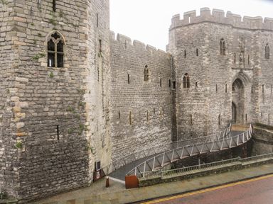 A stone fortress with a modern wooden footbridge leading to a large arched entrance at Llety Pen Deitsh 2 in Caernarfon