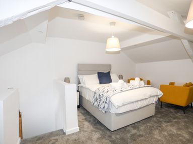 A bedroom with a double bed and two yellow armchairs at Llety Pen Deitsh 2 in Caernarfon