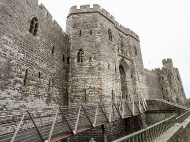 A stone castle with a metal bridge leading to an arched entrance at Llety Pen Deitsh 2 in Caernarfon