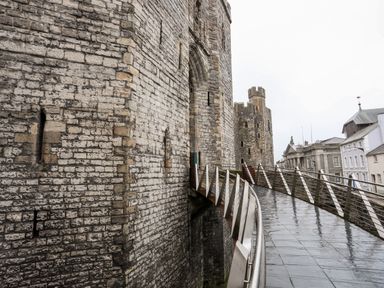 A stone castle wall with an arched entrance and a metal railing walkway leading to it at Llety Pen Deitsh 2 Caernarfon