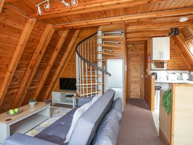 A living area with a gray couch coffee table with fruit spiral staircase and kitchenette at 171 Snowdonia View in Chwilog