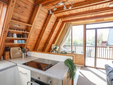 A kitchen area with a cooktop and utensils next to large glass doors opening to a deck at 171 Snowdonia View in Chwilog