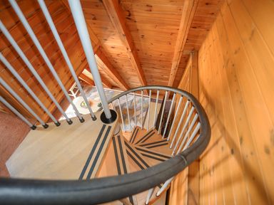 A spiral staircase in a wooden interior with a small table and chairs at 171 Snowdonia View in Chwilog
