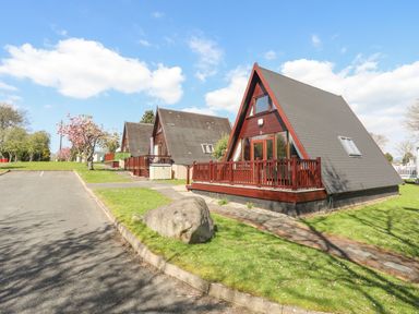 A row of a frame houses with wooden balconies next to a parking area at 171 Snowdonia View in Chwilog