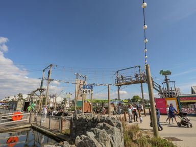 An outdoor adventure park with ropes course climbing wall and people walking near a boat hire sign at 171 Snowdonia View in Chwilog