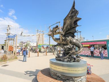 An outdoor area with a dragon statue a ropes course with people on it a boat hire sign and a refreshment kiosk at 171 Snowdonia View in Chwilog