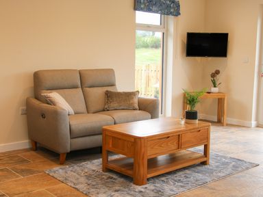 A sitting area with a two-seater sofa and wooden coffee table at Holly Lodge in Forden near Montgomery