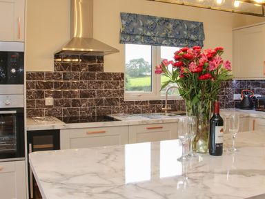 A kitchen with marble countertops flowers wine and glasses at Holly Lodge in Forden near Montgomery
