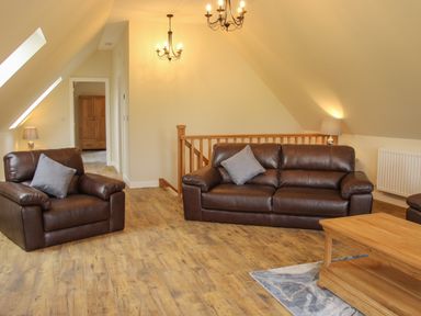 A living room with brown leather sofas wooden coffee table and wooden floor at Holly Lodge in Forden near Montgomery