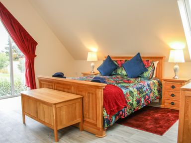 A bedroom with a wooden bed and bedside tables with lamps at Holly Lodge in Forden near Montgomery