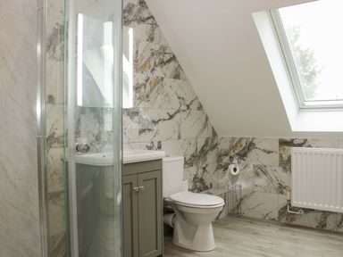 A bathroom with a toilet sink cabinet glass shower and a skylight at Holly Lodge in Forden near Montgomery