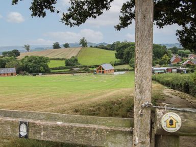 A rural landscape with fields trees a wooden fence and houses at Holly Lodge in Forden near Montgomery