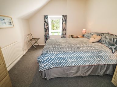 A bedroom with a double bed a window with curtains and a luggage rack at Grannys in Bushmills County Antrim