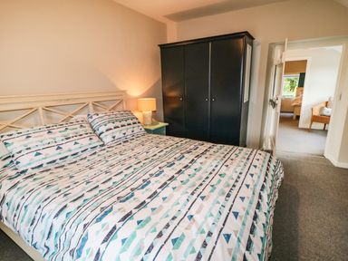 A bedroom with a bed a side table with a lamp and a black wardrobe at Grannys in Bushmills County Antrim