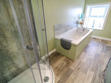 A bathroom with a shower enclosure bathtub and a window at Grannys Bushmills County Antrim