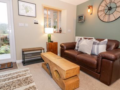 A living room with a brown leather sofa and wooden coffee table at Cwm Caeth Cottage in Nantmor near Beddgelert