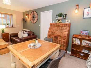 A living room with a brown leather sofa wooden table and wooden cabinet at Cwm Caeth Cottage Nantmor near Beddgelert