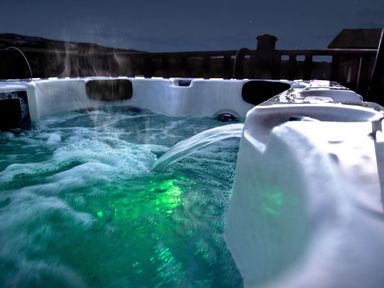 A bubbling hot tub with water jets and green underwater lights outside at Chi Prenn Byhan in Tintagel