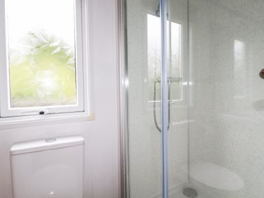 A bathroom with a shower enclosure and toilet at Orchard View in Bossiney near Tintagel