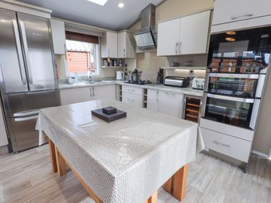 A kitchen with a table covered with a patterned tablecloth and appliances at Windermere View Pony Meadow 37 White Cross Bay near Windermere