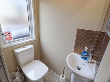 A small bathroom with a toilet and a sink with hand soap at Windermere View in Pony Meadow 37 White Cross Bay near Windermere