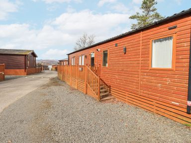 A row of wooden lodges along a gravel and paved road at Windermere View in Pony Meadow 37 White Cross Bay near Windermere