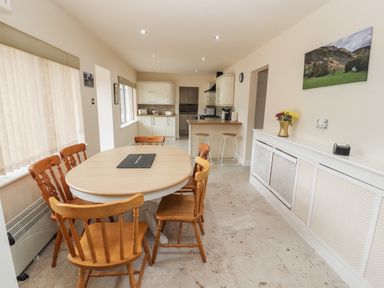 A kitchen diner with a wooden dining table and chairs two bar stools and kitchen units at Awel Y Berwyn in Llangynog
