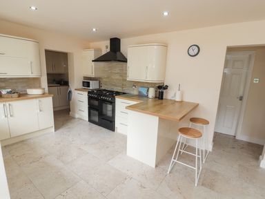 A kitchen with cream cabinets a black stove a microwave and two stools at Awel Y Berwyn in Llangynog