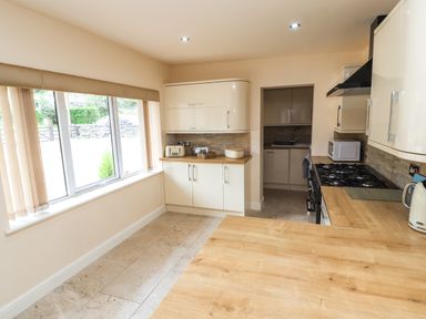 A kitchen with wooden countertops cream cabinets a gas stove microwave and a window at Awel Y Berwyn Llangynog