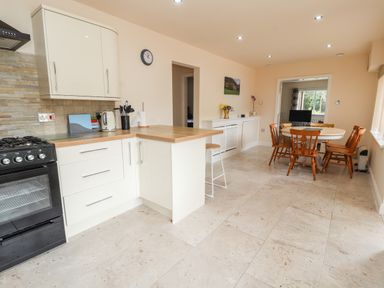 A kitchen and dining area with white cabinets wooden countertop dining table and chairs at Awel Y Berwyn in Llangynog