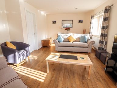 A living room with sofas a coffee table and curtains at Awel Y Berwyn in Llangynog