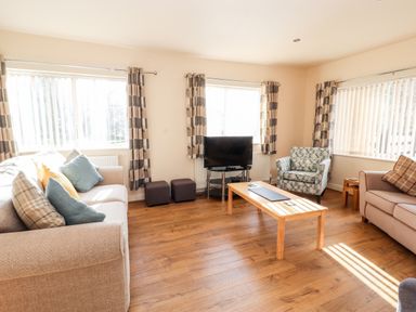 A living room with two sofas an armchair wooden coffee table and a television at Awel Y Berwyn in Llangynog