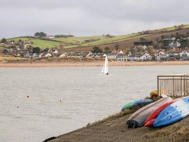 A view of a river or lake with sailboats and kayaks near a shore with houses and hills in the background at Stonewood Lodge in Woolsery