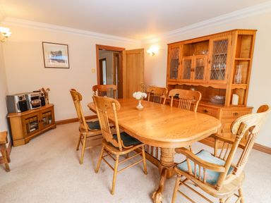 A dining room with a wooden table and chairs a wooden cabinet and a stereo system at Corner House in Cinderford