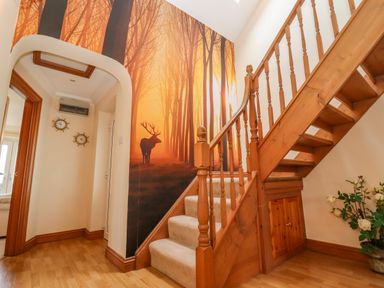 A staircase with wooden railing and a mural of a deer in a forest at Corner House in Cinderford