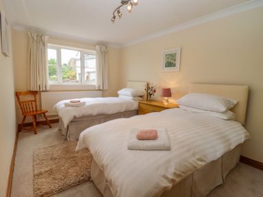 A bedroom with two single beds a wooden chair and a window at Corner House in Cinderford