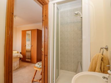 A bathroom with shower and sink next to a bedroom with wardrobe and bed at Corner House in Cinderford