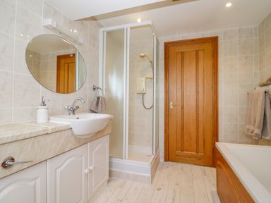 A bathroom with a shower stall sink bathtub and wooden door at Corner House in Cinderford