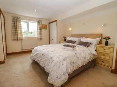 A bedroom with a double bed bedside tables and a window with checked curtains at Corner House in Cinderford