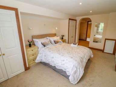 A bedroom with a double bed bedside tables and a mirror at Corner House in Cinderford