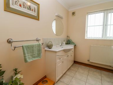 A bathroom with a white vanity unit sink mirror window and a towel hanging on a rail at Corner House in Cinderford